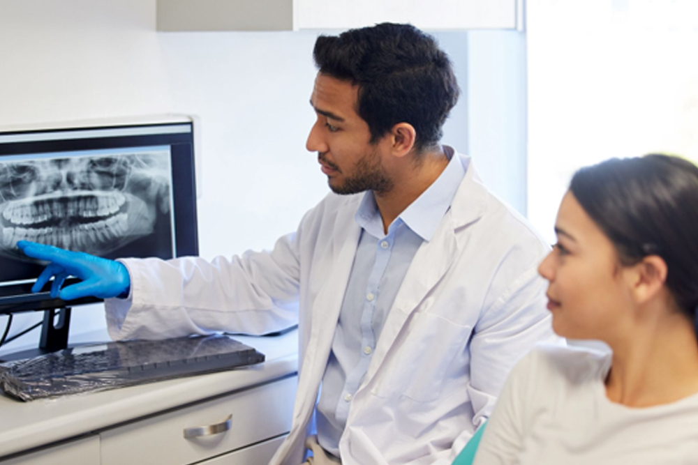 Dentist reviewing a dental X-ray with a patient during a root canal consultation